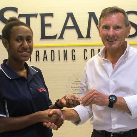 Man and woman jointly holding up an award made of clear material
